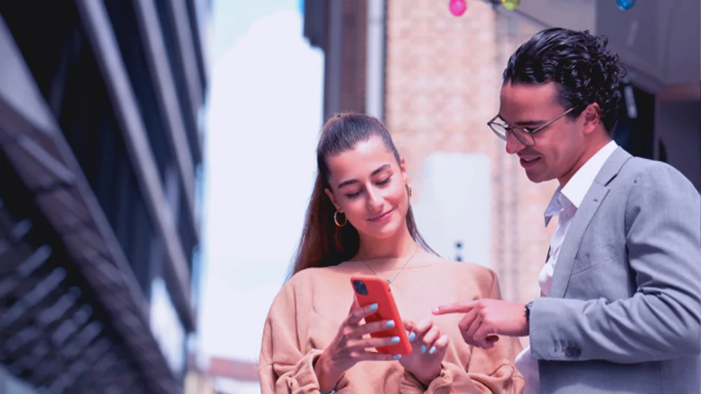 Zwei junge Personen beraten sich über einem Smartphone-Bildschirm
