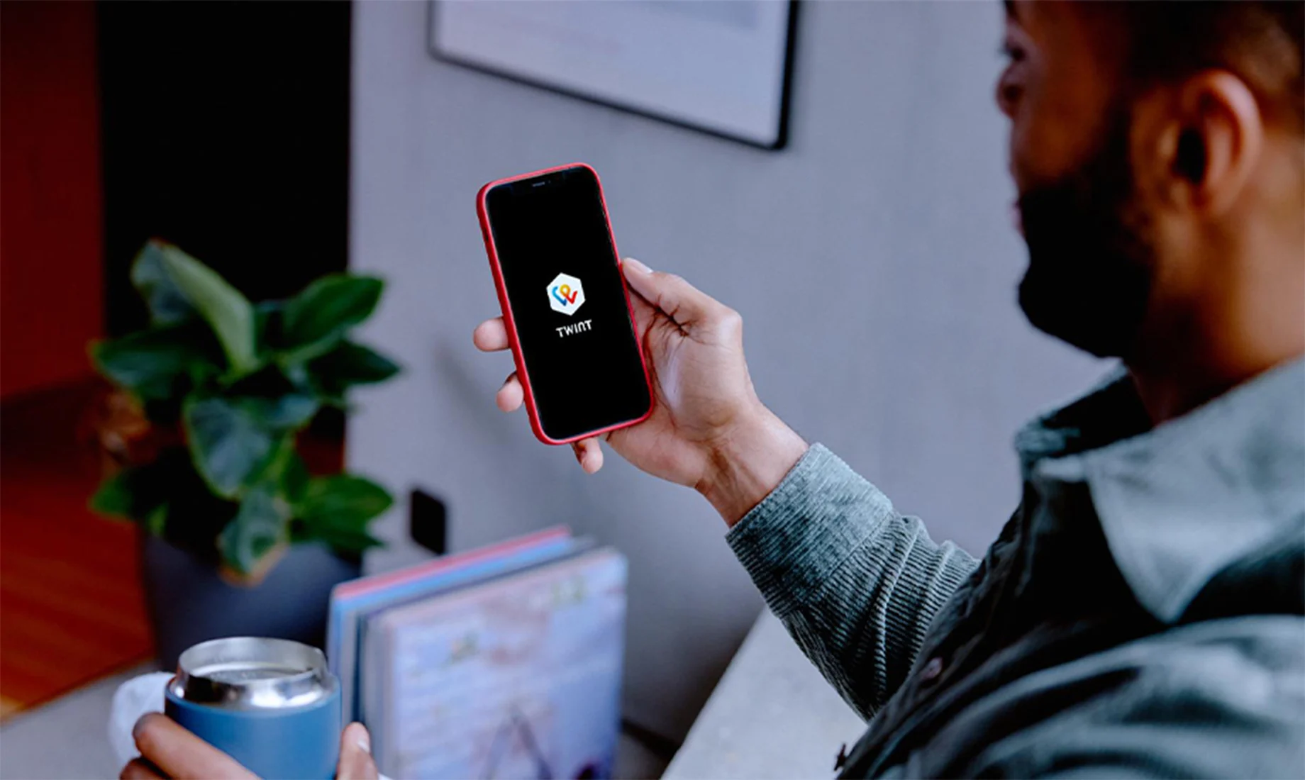 Ein Mann hält ein Handy mit TWINT Logo auf dem Screen